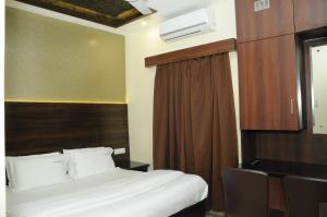 a bedroom with a bed and a brown curtain at Hotel Grand Parkway in Tambaram