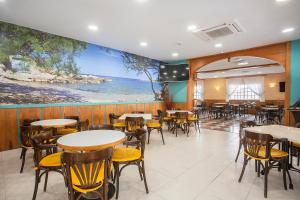 a restaurant with tables and chairs and a large painting on the wall at Hotel Playa Sol in El Arenal