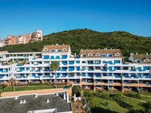 ein großes weißes Gebäude mit einem Berg im Hintergrund in der Unterkunft Sea view apartment with great terrace and 4 pools - Duquesa Suites 430 in Manilva