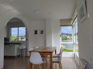 a dining room with a wooden table and white chairs at Playa de Miño in Miño