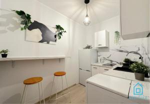 a white kitchen with two stools and a counter at Piggy Room - 3 km to Baltic Sea in Gdańsk