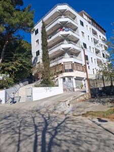 a large white building with a tree in front of it at Jozi Kaiser Apartment 4 in Durrës +6 photos