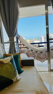 a bed with a hammock in a room with a window at Apto Lindo e Amplo, 150m beach in Cabedelo +45 photos