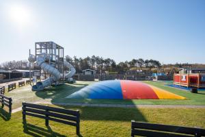 a playground with a colorful play structure in a park at Chalet aan de bosrand in De Koog