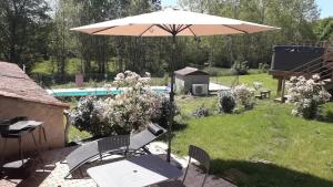 eine Terrasse mit Sonnenschirm und Tisch und Stühlen in der Unterkunft Charmante maison avec piscine à Chalandray, 25 m² in Chalandray