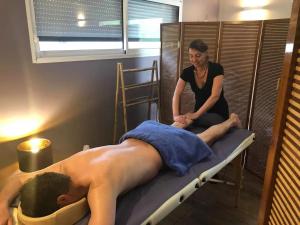 Eine Frau, die einem Mann eine Massage auf einem Bett gibt. in der Unterkunft Charmante maison avec piscine à Chalandray, 25 m² in Chalandray