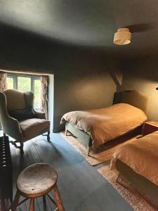a bedroom with two beds and a chair at Highend Cotswold Barn near Soho Farmhouse & Daylesford in Duns Tew