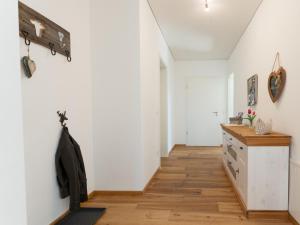 a hallway with white walls and a wooden floor at Ferienwohnung Anemone - 4 Zimmer mit Bergblick & Alpenflair in Germaringen