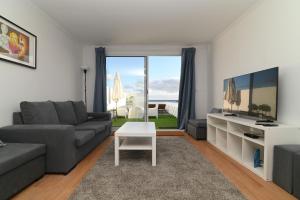 ein Wohnzimmer mit einer Couch, einem Fernseher und einem Tisch in der Unterkunft Lagoa Sea View by Vacationy in Lagoa