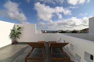 einen Balkon mit vier Holzstühlen an einer weißen Wand in der Unterkunft Lagoa Sea View by Vacationy in Lagoa