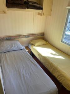 two beds in a small room with a window at Vintage Forest Chalet in IJhorst +18 photos