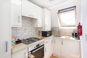 Una cocina con gabinetes blancos y un horno de estufa. en Euston Modern Apartments, en Londres