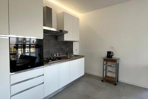 a kitchen with white cabinets and a stove top oven at Lake view apartment in Dormelletto