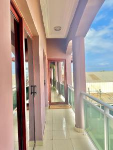 a balcony of a building with pink walls and glass doors at Appartement Rosa in Pointe-Noire
