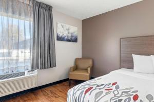 a bedroom with a bed and a chair and a window at Red Roof Inn Charlotte - University in Charlotte