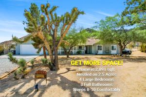 un cartello di fronte a una casa con alberi di Epic Views, Huge House, Acres of J-Trees to explore, Hot Tub, Pool, AC, and Mini-Golf a Joshua Tree