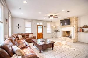 Una sala de estar con un sofá de cuero y una chimenea. en Gardens of Barons Creek - UNIT C, en Fredericksburg