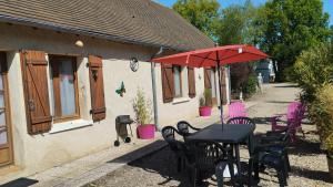 a table and chairs with a red umbrella at Maison N 2 Du Bas Coudreau in Rosnay