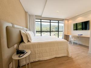 イタペマにあるSuíte com vista para montanhas no Blue Sea Hotel, beira-mar+lazer completoのベッドと大きな窓のある寝室