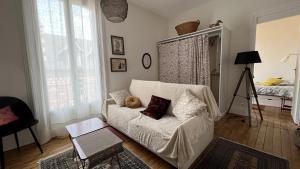 Appartement ancien cosy في دْييب: غرفة معيشة مع أريكة بيضاء مع وسادتين