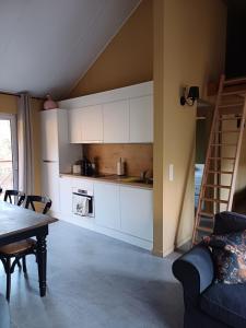 a kitchen with white cabinets and a table and a ladder at Châlet des Cerfs Durbuy in Somme-Leuze