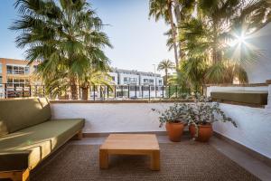 a couch and a coffee table on a balcony with palm trees at K-PALM by Nuka Homes in Jávea