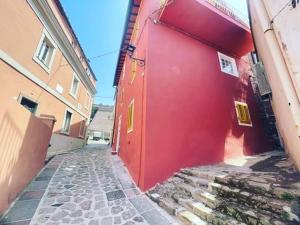 ein rotes Gebäude mit einer roten Tür in einer Straße in der Unterkunft Casa Mareo in Capraia