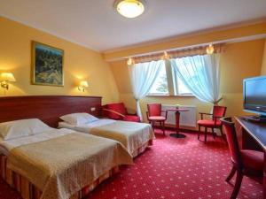 a hotel room with two beds and a flat screen tv at Pensjonat Solis Sarbinowo in Sarbinowo