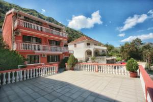 a large red building with a balcony and a house at Apartments Simun in Kotor