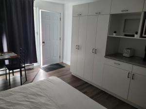 a bedroom with white cabinets and a table and a bed at Hébergements ASLC Baie-Comeau in Baie-Comeau