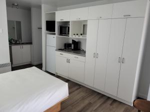 a white bedroom with white cabinets and a bed at Hébergements ASLC Baie-Comeau in Baie-Comeau
