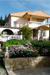 a large white house with a garden with flowers at Ferienwohnung mit Privatpool Casa Wende in Benaguacil