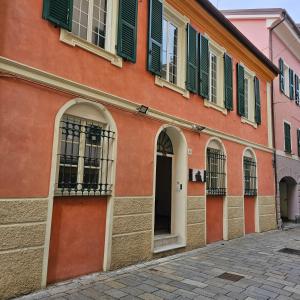 un edificio arancione con finestre con persiane verdi e una porta di Blu Oltremare camere bijoux a Varazze
