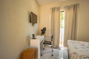 una camera con scrivania, letto e TV di Casa no Perequê Guarujá c/ Wi-Fi e Churrasqueira a Bertioga