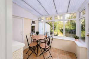 a table and chairs in a room with windows at Cosy country cottage, nearby beaches attractions A55 in Llysfaen