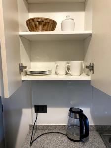 a kitchen cupboard with plates and dishes on it at Cálido y céntrico dpto, a pasos de Paicavi in Concepción