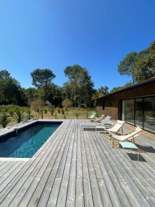 una terrazza in legno con sedie e una piscina di La Villa des Chênes ad Audenge