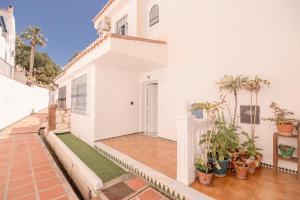 a white house with a porch with potted plants at Casa Melina in Cala del Moral