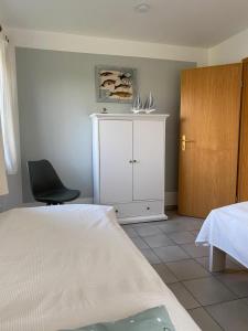 a bedroom with a bed and a chair and a cabinet at Kamin, Wintergarten & Sonnenterrasse in Wenkendorf auf Fehmarn