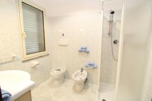 a white bathroom with a toilet and a shower at Farri's Apartment in La Caletta