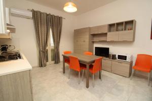 a kitchen with a wooden table and orange chairs at Farri's Apartment in La Caletta +19 photos