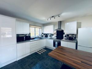 a kitchen with white cabinets and a wooden table at St Peter's Riverside Apartment Newcastle Quayside Free Parking in Saint Peters