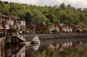 a boat docked in a river next to houses at St Peter's Riverside Apartment Newcastle Quayside Free Parking in Saint Peters