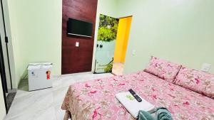 a bedroom with a pink bed with a remote control on it at Pousada coração do Jalapão in São Félix do Tocantins