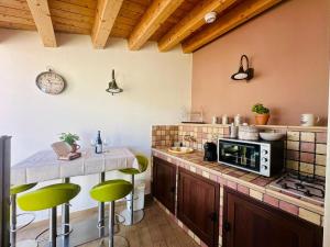 a kitchen with a counter with a microwave and green stools at Holiday House Valpiè in Avola