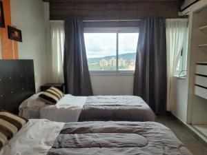 two beds in a room with a window at Los Naranjos in San Salvador de Jujuy