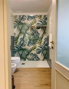 a bathroom with a mural of palm trees on the wall at Ca' dal Pum - Lake Orta - Elegant holiday home in Gozzano