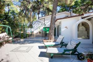 a patio with two chairs and a tree at Sani Villa Suave with pool in Sani Beach