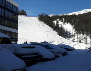 ヴァールにあるImm Pelvoux 1 Studio familial pied des pistesの雪山の横に停車する車列