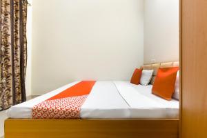 a bed with orange and white pillows on it at Hotel O Sabtera Homes in Kharar +32 photos